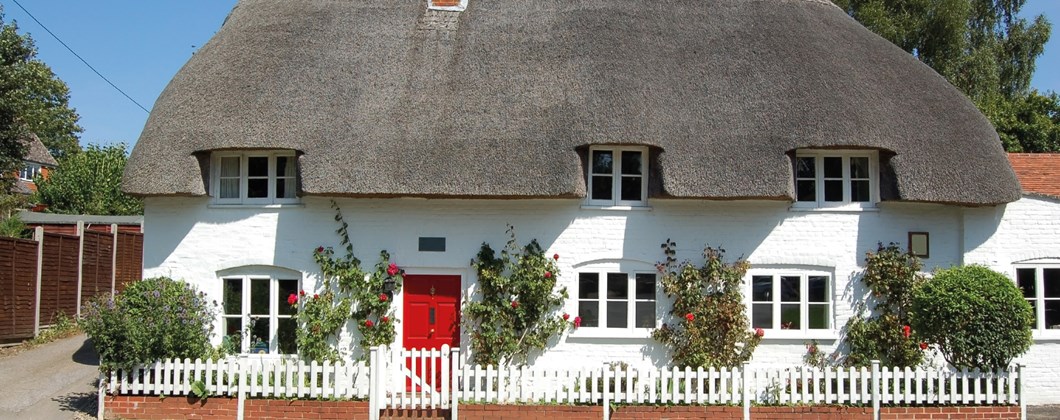thatched cottage with white walls and red front door