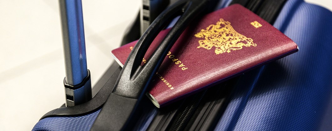 Close-up image of a blue travel suitcase with red passport.